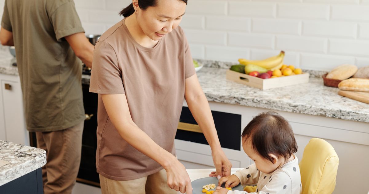 Mamma che imbocca con frutta fresca tagliata in modo sicuro