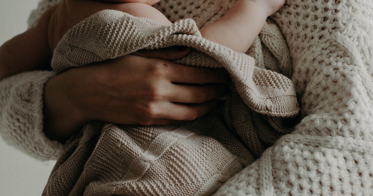 Donna che tiene in braccio il suo bebè in posizione fisiologica