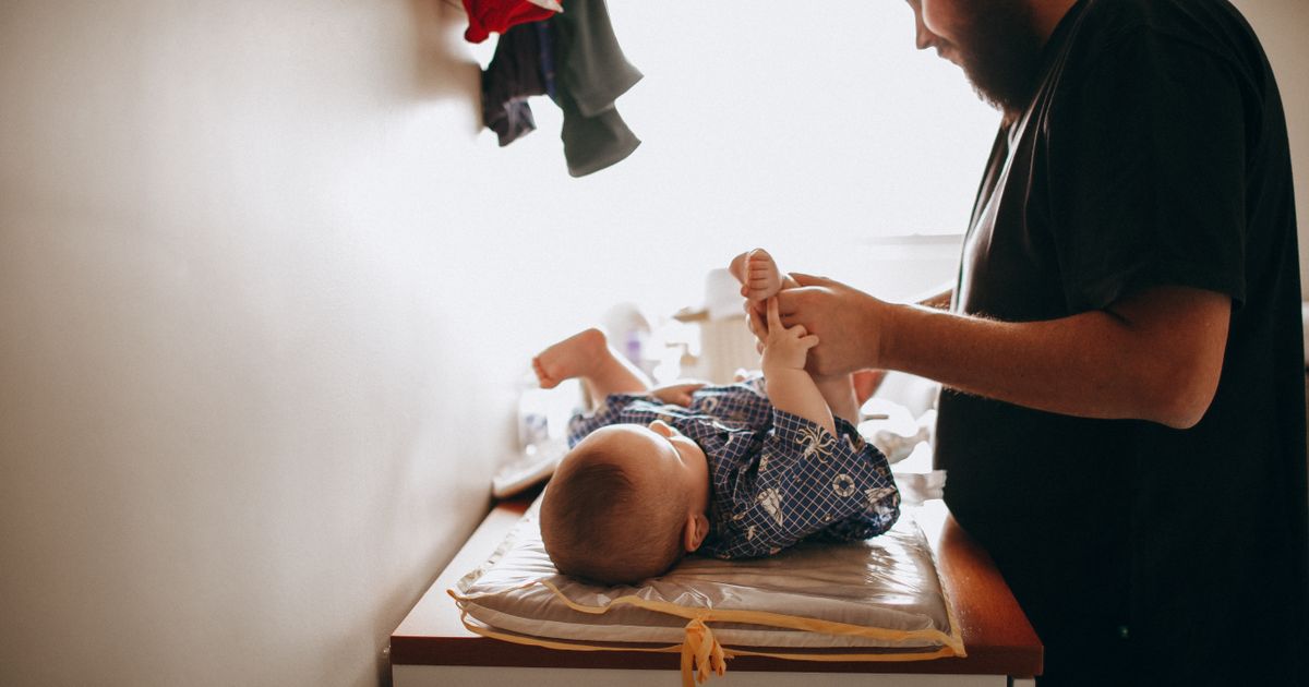Papà che cambia il pannolino al neonato con gesti delicati