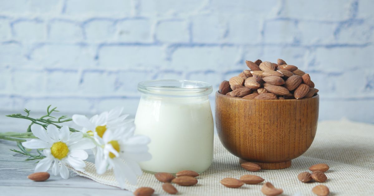 Ciotola di mandorle accanto a un bicchiere di latte vegetale