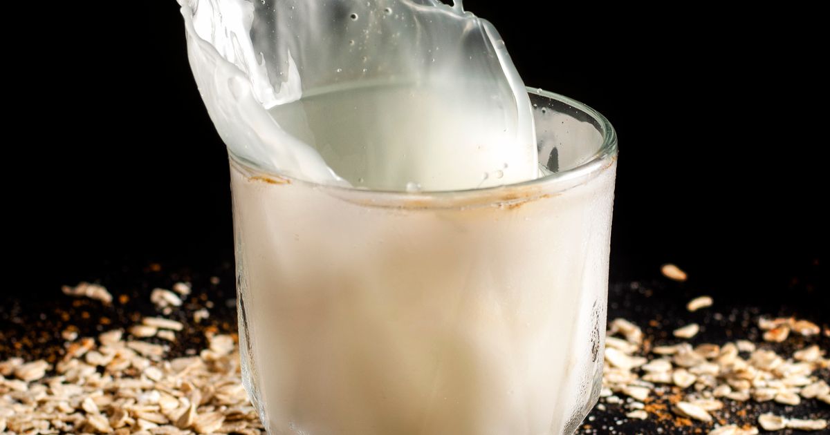 Latte d'avena versato in un bicchiere su un piano chiaro